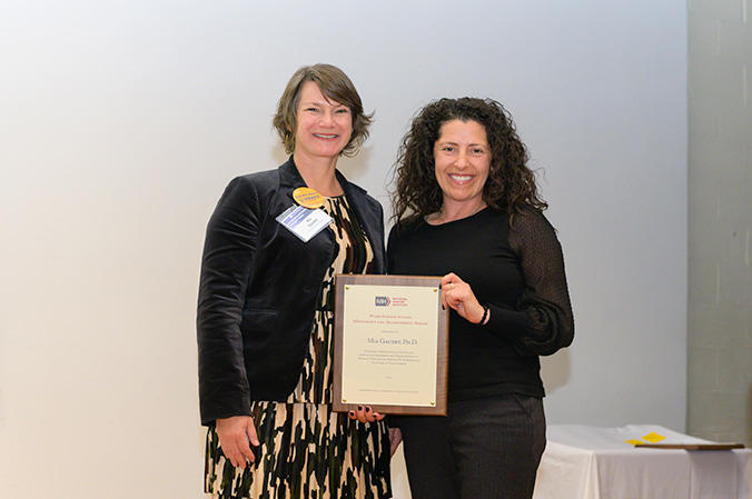Two women holding an award. 
