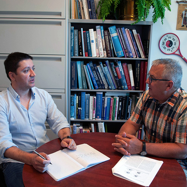 Two men smiling in an office environment.