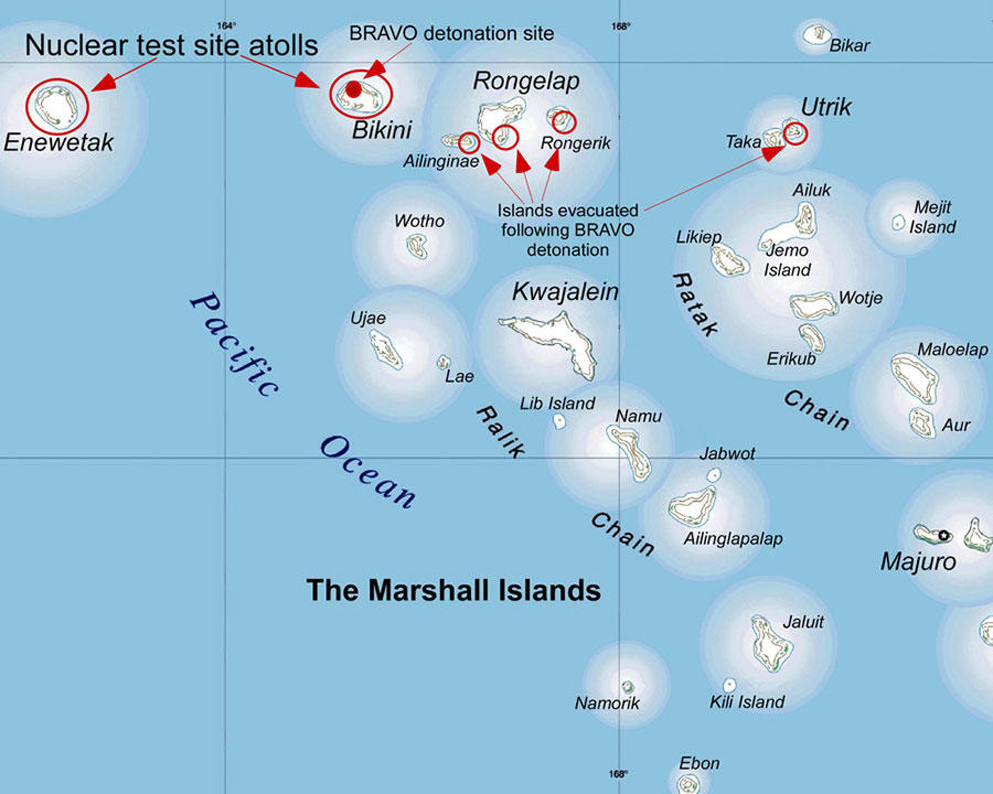 A map of the Marshall Islands. Each island is named and is a white shape on top of blue, representing the Pacific Ocean (which is also labeled). A ground of islands at the top of the map labels the two nuclear test site atolls (Enewetak and Bikini) and the four islands evacuated following the BRAVO detonation (Ailinginae, Rongelap, Rongerik and Utrik.