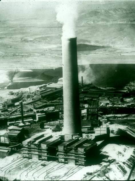Historical photo of a copper smelter billowing smoke.