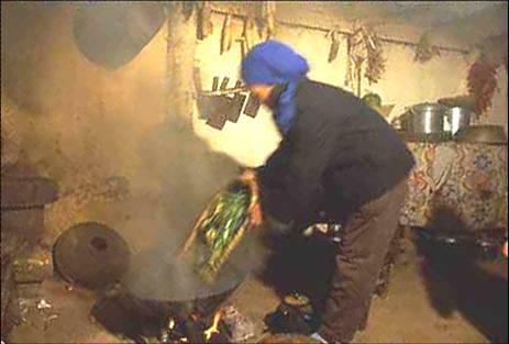 A woman with her face covered dumping food into a smoky wok.