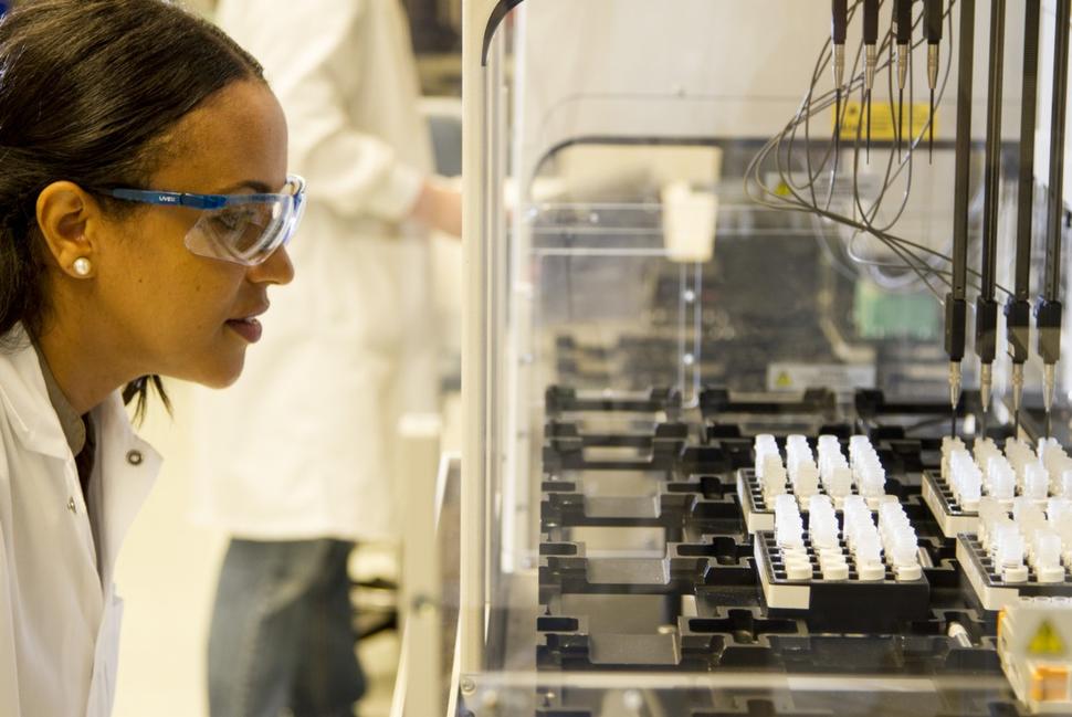 Technician watches robot selecting DNA for amplification in CGR.