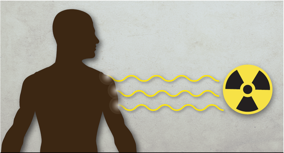 silhouette stands at a distances from yellow and black radiation symbol, received yellow rays from the symbol