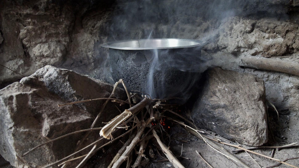 photograph of a cooking stove with smoke from burning wood