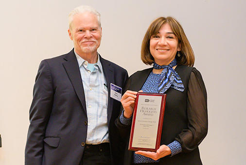 A man and woman holding an award. 