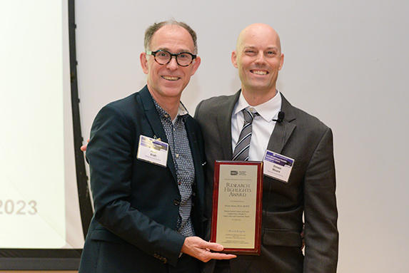 Two men holding an award. 