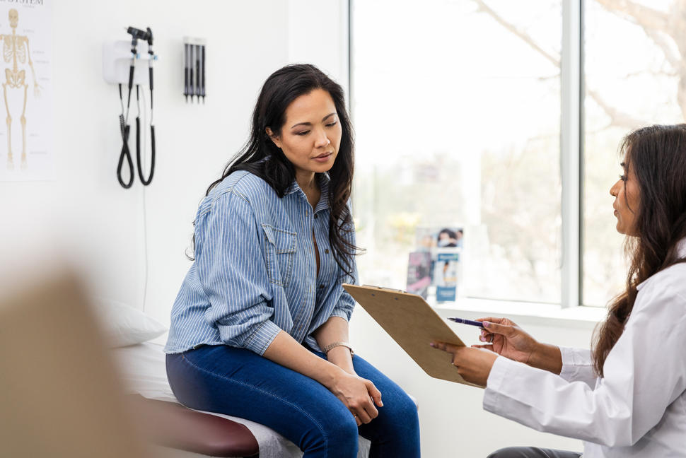 photograph of a woman seated in exam room with female doctor
