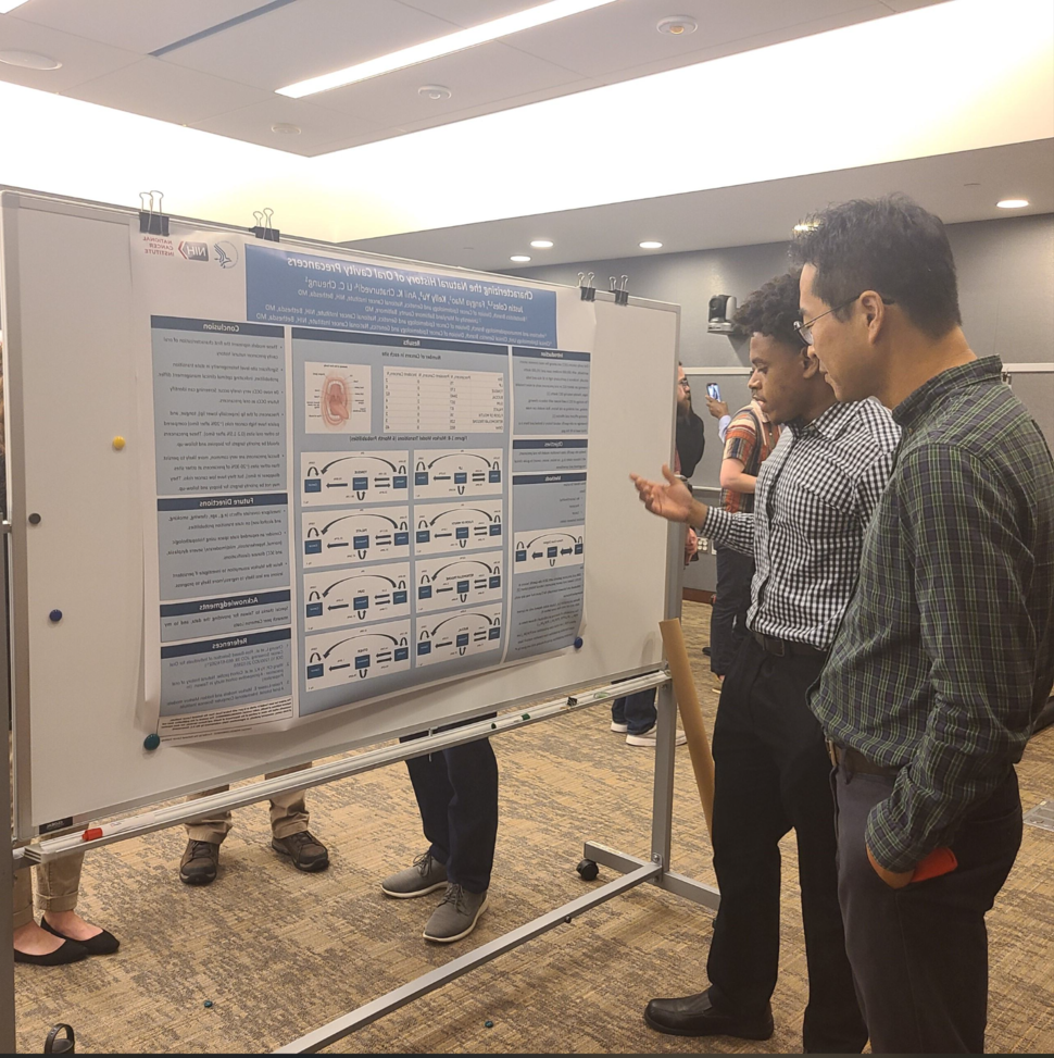 Justin Coles, summer intern, presents his poster to interested attendee