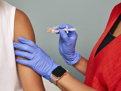 A medical professional with gloves on is administering a vaccination shot into someone's arm