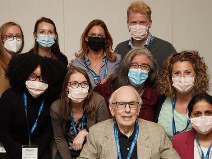 Photograph of a team of individuals standing with one man seated