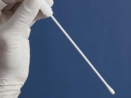 Gloved hand holding a medical swab