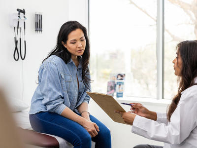 photograph of a woman seated in exam room with female doctor