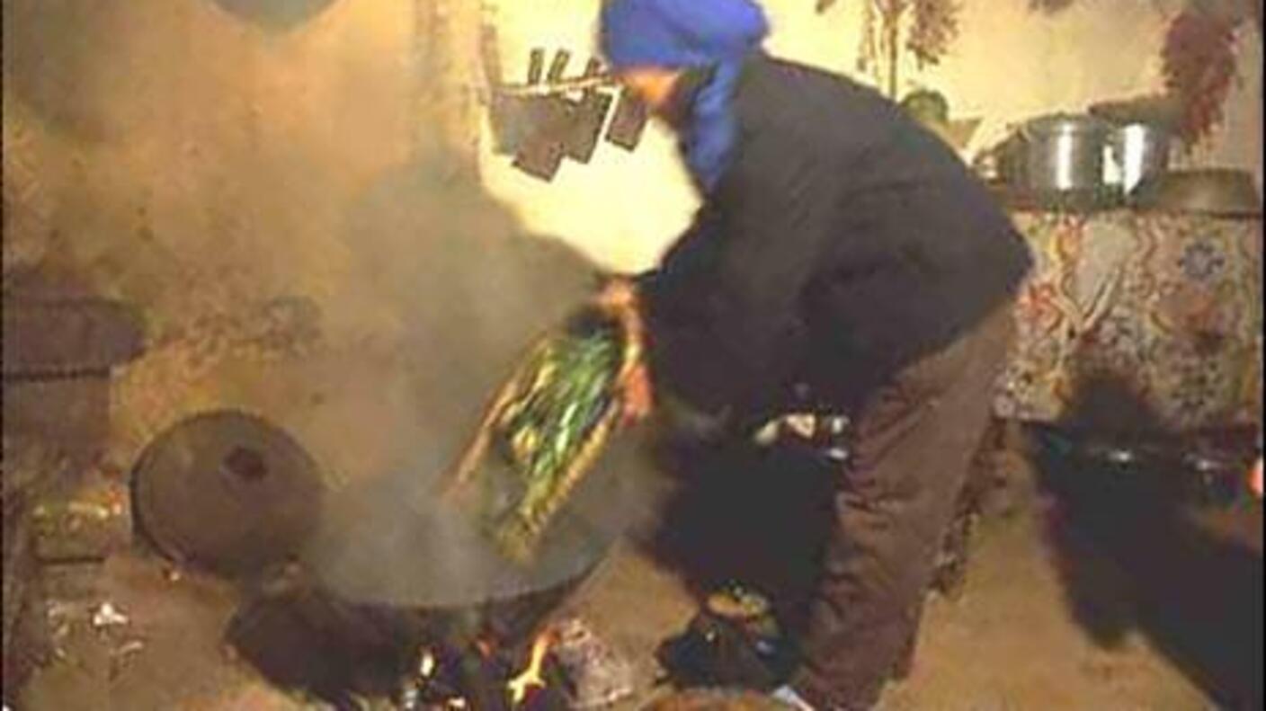 woman cooking in a wok with a lot of smoke