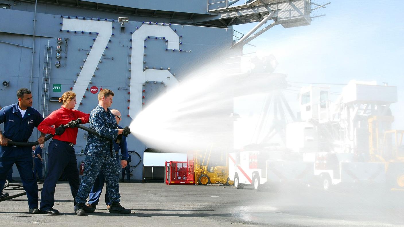 A U.S. Airmen aim a hose shooting firefighting foam. 