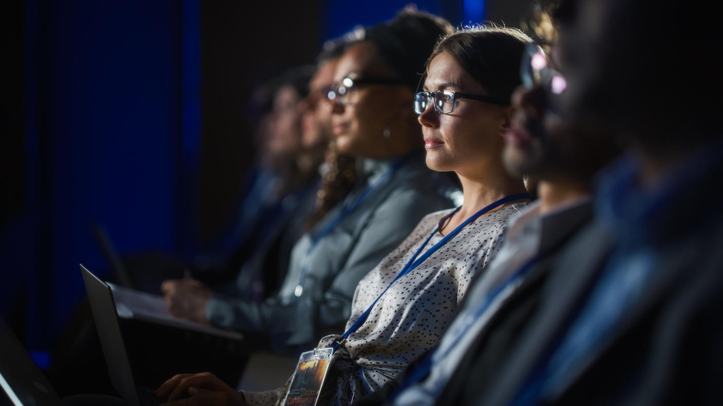Row of people sitting at a conference.
