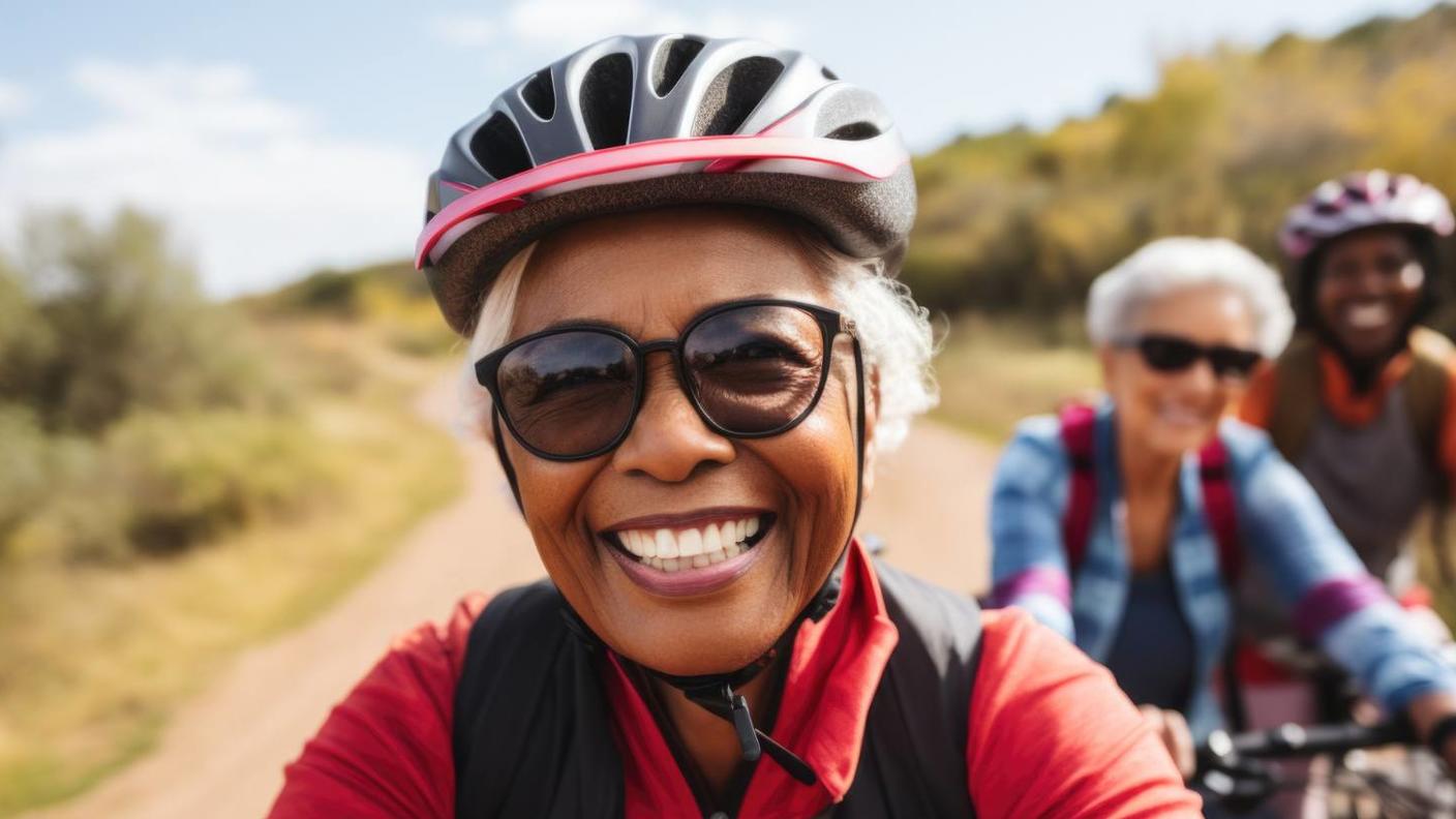 Portrait of happy senior woman in cycling helmet riding outdoors.