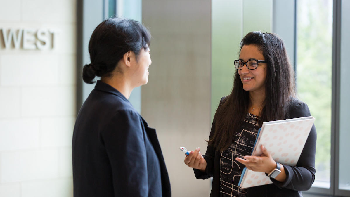 Two female fellows talking in the hallway
