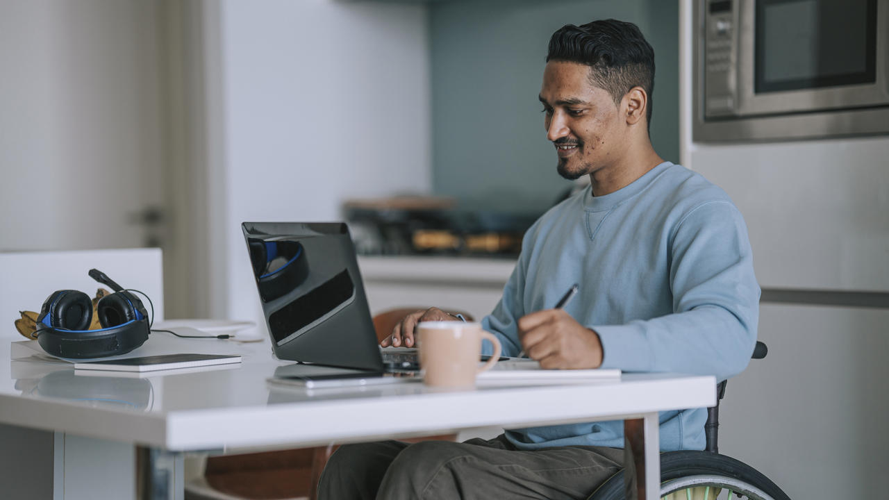Man in wheelchair working on a laptop.