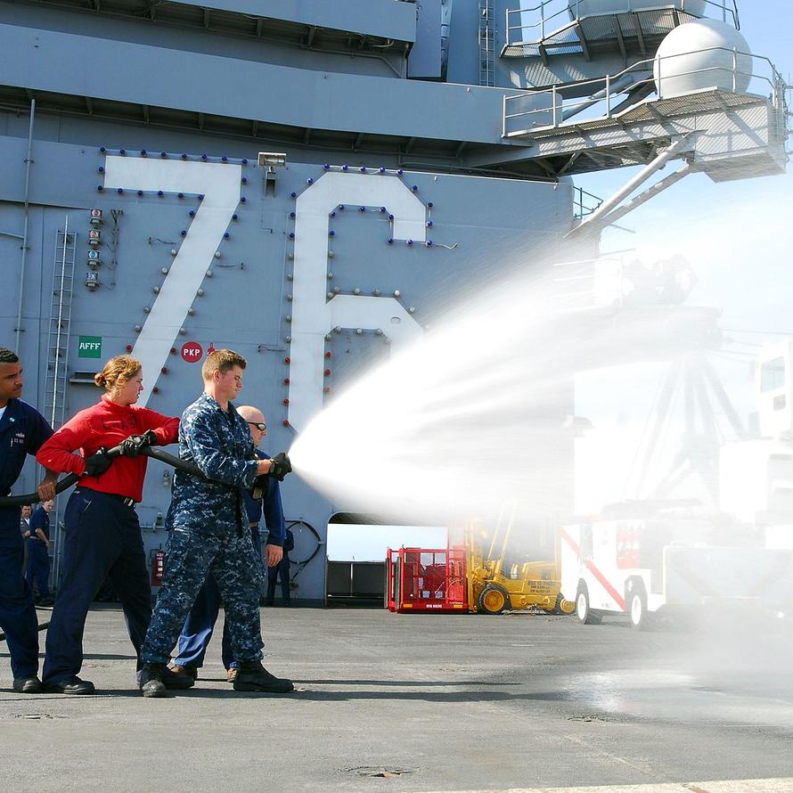 A U.S. Airmen aim a hose shooting firefighting foam. 