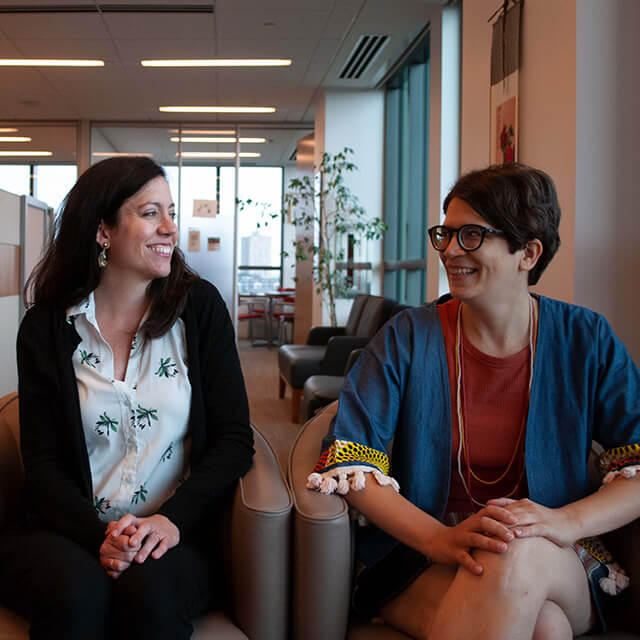 Two women smiling in an office environment.