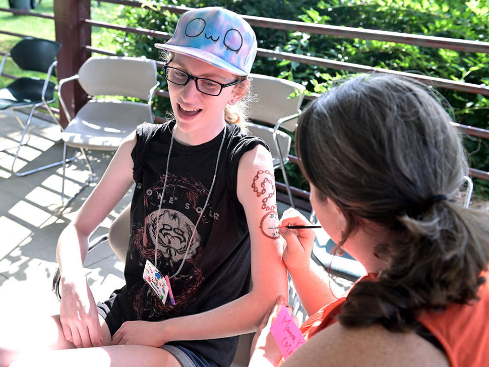 Maura Kate Costello paints design on camper's arm at Camp Fantastic.