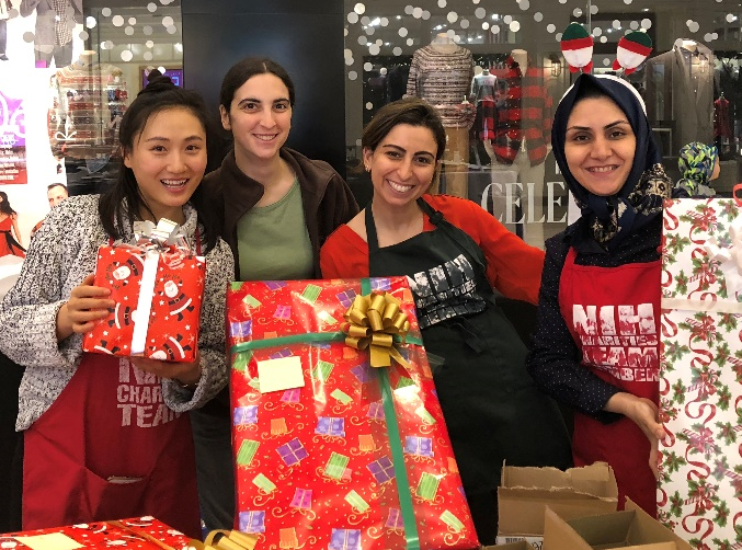 Photo of four women holding wrapped presents.