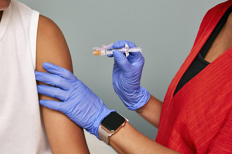 A medical professional with gloves on is administering a vaccination shot into someone's arm