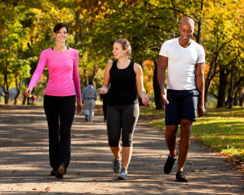 A group of three adults walking in a park together.