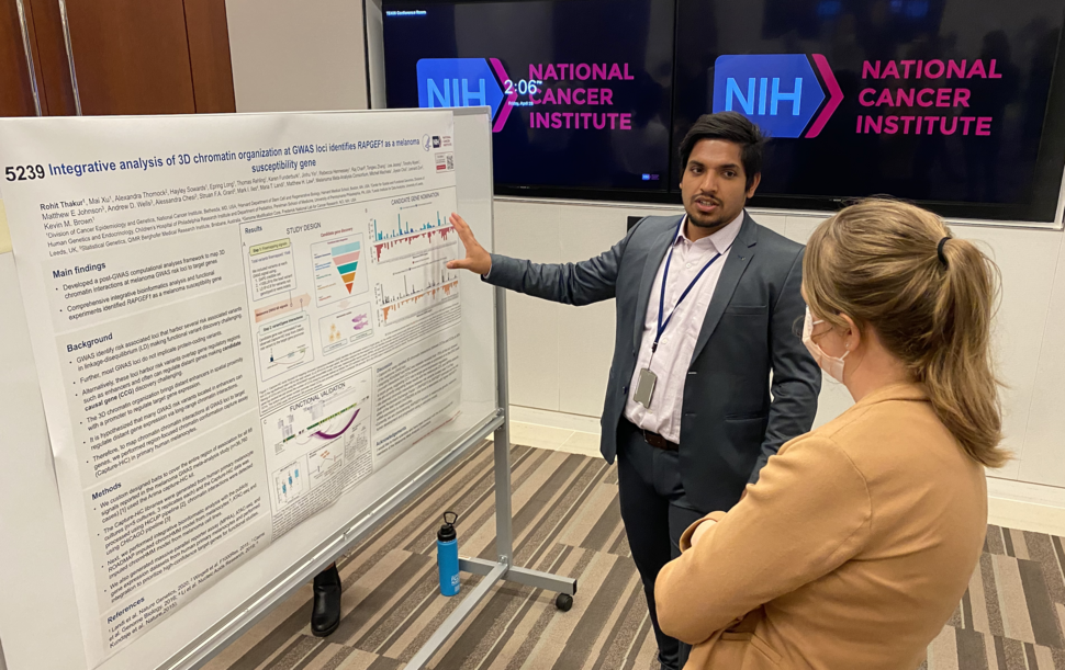 Rohit Thakur points to his poster as he explains his research.