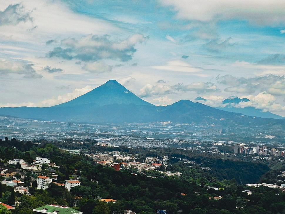 Guatemala City skyline with mountains and volcanoes in the background.