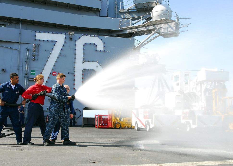 A U.S. Airmen aim a hose shooting firefighting foam. 