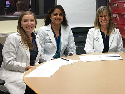 clinicians in lab coats sitting at a table